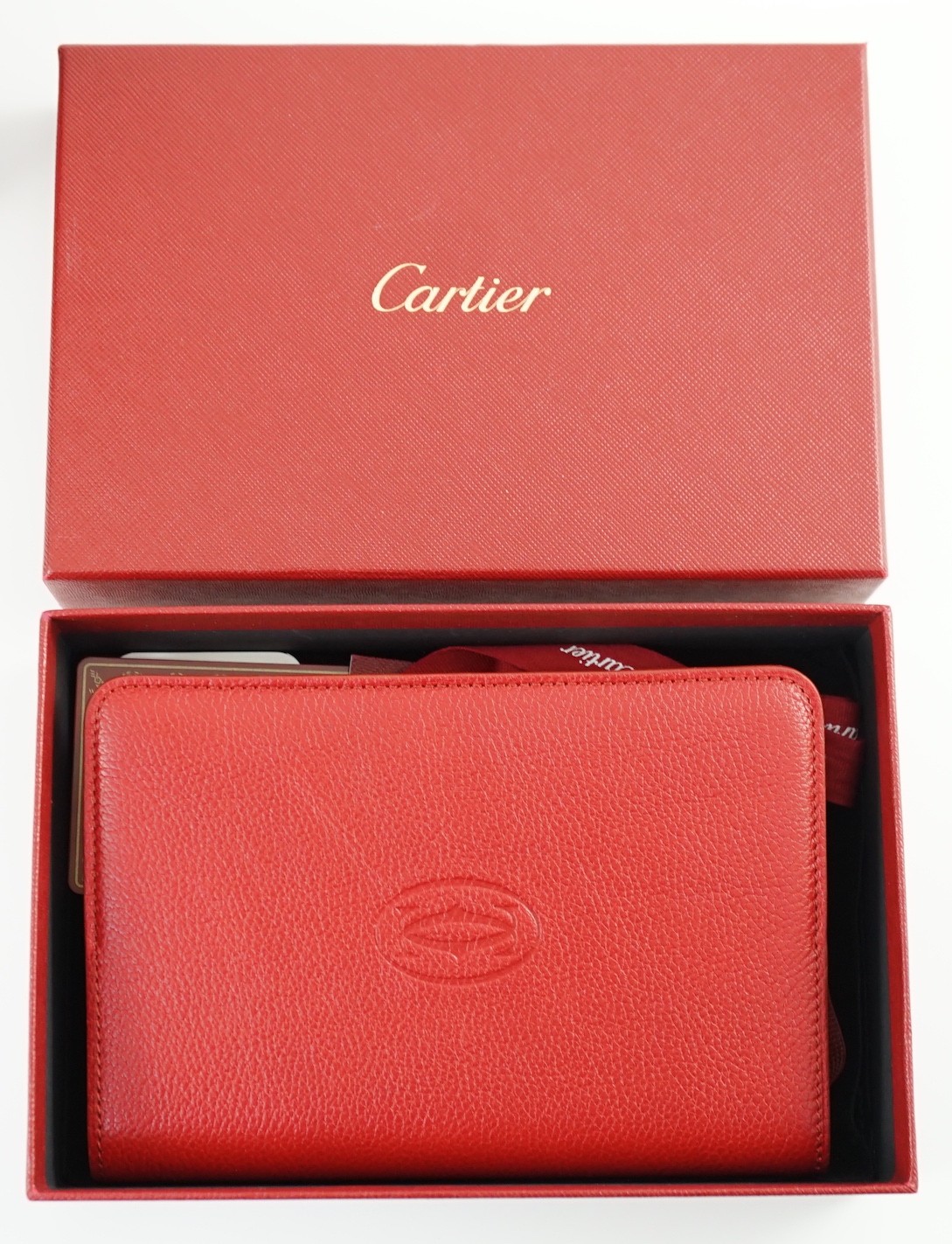 A Cartier red leather notebook, boxed, with bag, papers and certificate